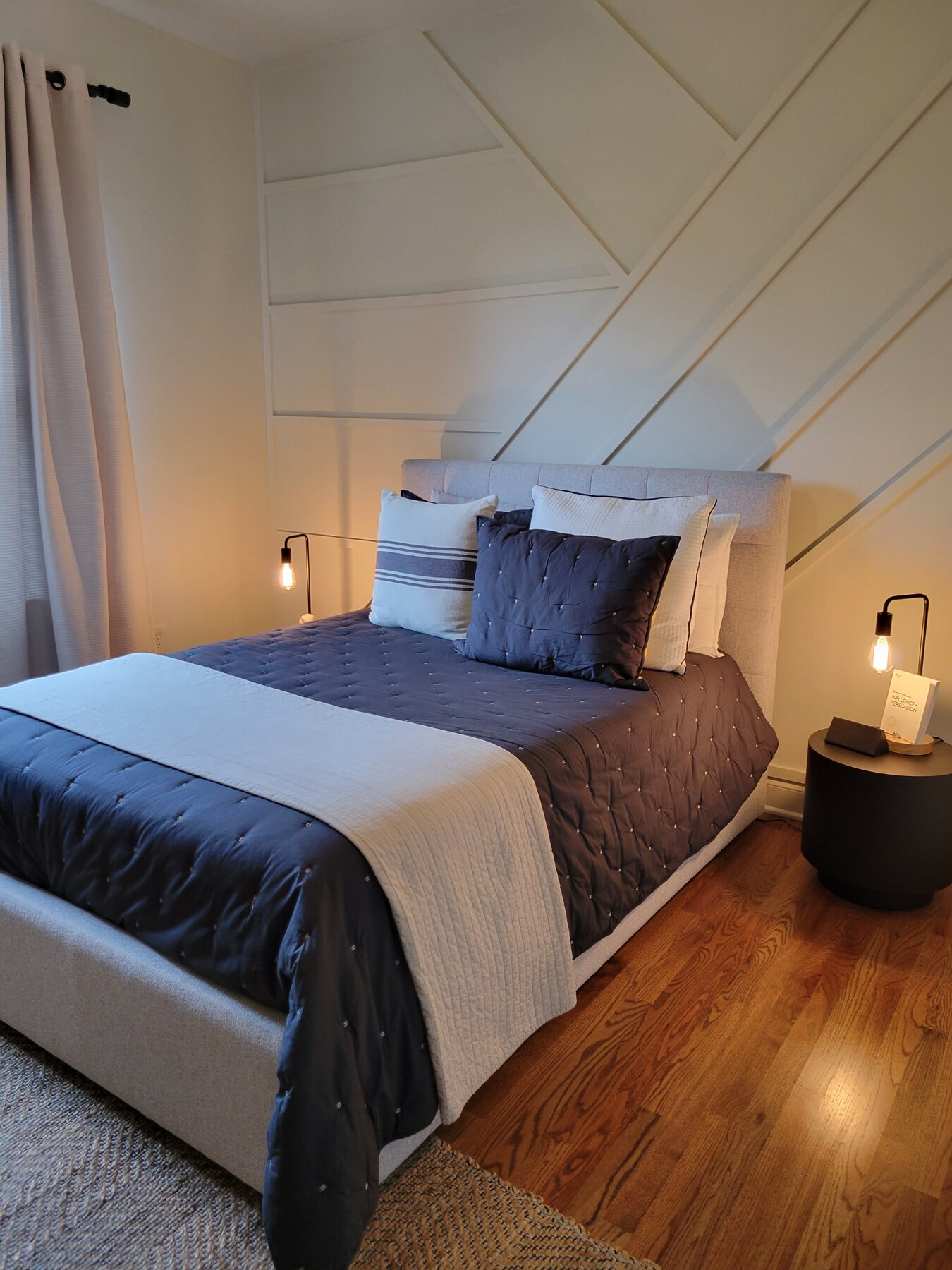 Moody bedroom with charcoal textiles and warm wood flooring